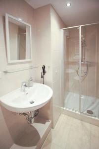 ein weißes Bad mit einem Waschbecken und einer Dusche in der Unterkunft Schiller-Quartier 15 in Bremerhaven