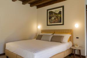 1 dormitorio con 1 cama blanca y una pintura en la pared en Crystal Luxury House en Fiume Veneto