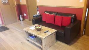 a living room with a black leather couch and a coffee table at Leven and Linnhe Apartments, West Highland Way Holidays in Kinlochleven
