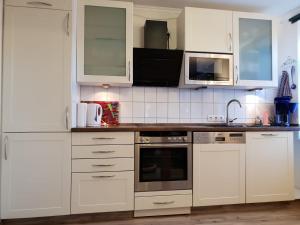 uma cozinha com armários brancos e electrodomésticos de aço inoxidável em Ferienwohnung "Mia" em Quedlinburg