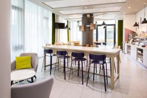 uma cozinha com um bar com bancos e uma sala de jantar em Aparthotel Adagio access München City Olympiapark em Munique