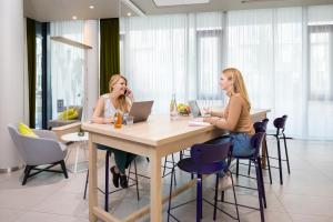 two women sitting at a table with their laptops at Aparthotel Adagio access München City Olympiapark in Munich