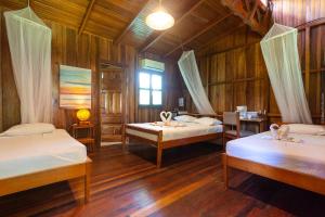 a room with three beds in a room with wooden walls at Escape Caribeño in Puerto Viejo