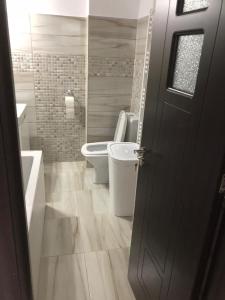 łazienka z 2 toaletami, umywalką i drzwiami w obiekcie Ana Studio Apartment w mieście Gałacz