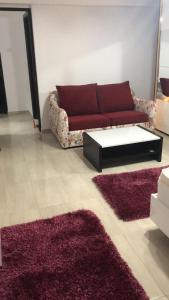 ein Wohnzimmer mit einem roten Sofa und 2 Teppichen in der Unterkunft Ana Studio Apartment in Galaţi