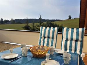 Unterkirnach的住宿－Ferienwohnung am Bach，阳台上配有一张带盘子和椅子的蓝色桌子