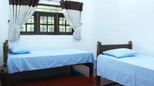 two beds in a room with a window at Grand Villa in Anuradhapura