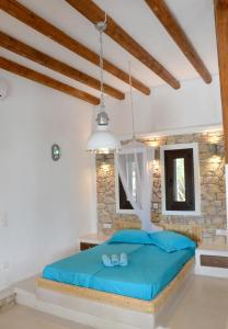 a bedroom with a blue bed and a stone wall at STUDIOSWORX Apartments in Ios Chora