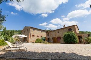 a building with chairs and an umbrella in front of it at BIOAGRITURISMO la Collina Casa Romeo in Larciano