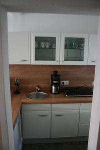 een keuken met witte kasten en een wastafel bij Ferienwohnung Am See 55 in Bad Saarow