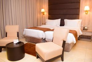 a hotel room with two beds and two chairs at Monty Suites & Golf in Uyo +34 photos