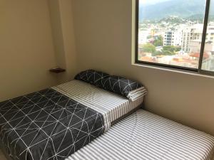 a small bedroom with a bed and a window at EDIFICO EL PEÑON DEL RODADERO APTO. 405A in Santa Marta