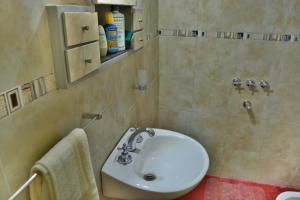ein Badezimmer mit einem weißen Waschbecken und einer Dusche in der Unterkunft La Casa de Huéspedes in Santa Teresita
