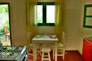 eine Küche mit einem Tisch, Stühlen und einem Herd in der Unterkunft La Casa de Huéspedes in Santa Teresita