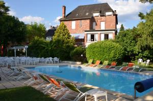 a swimming pool with chairs and a house in the background at LogisHotels Le Relais du Quercy in Meyssac