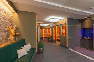 a lobby with a green couch and some plants at Hotel Braunschweiger Hof in Bad Harzburg