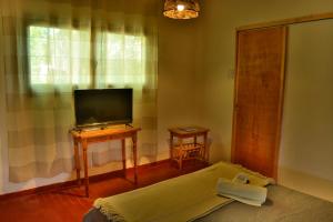 Una sala de estar con una cama y un televisor. en La Casa de Huéspedes, en Santa Teresita