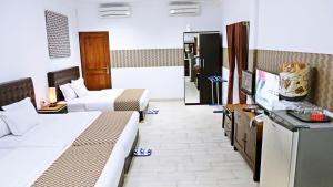 a hotel room with two beds and a flat screen tv at BeOne House Jogja in Yogyakarta