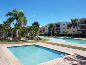 a swimming pool in a resort with palm trees and buildings at Paradise 3 cerro Altos in Santiago de los Caballeros
