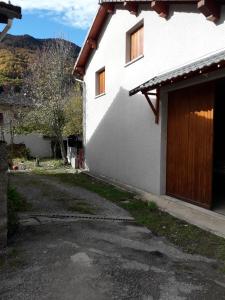 a white house with a wooden door and a driveway at L'Or de Fabiol in Orlu