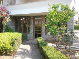 a front door of a house with a tree and bushes at Maisonette Afroditi in Perea