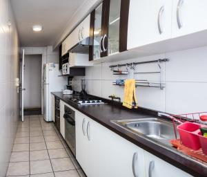 una cocina con armarios blancos y fregadero en Zenteno Apartments, en Santiago