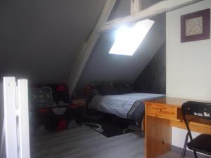 a small attic bedroom with a bed and a desk at chez christophe in Beauchêne