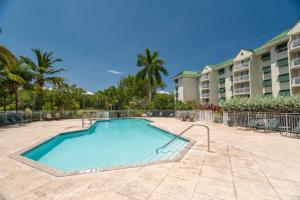 una grande piscina in un cortile con un edificio di Sunrise Suites Tierra Bomba Suite #403 a Key West