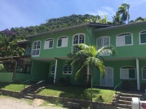 a green house with a palm tree in front of it at Marencanto Pousada in Ubatuba