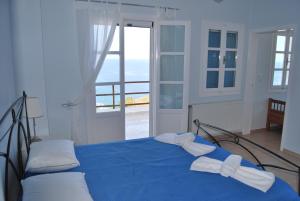 a bedroom with a blue bed with a view of the ocean at BAY VIEW HOUSE in Megas Gialos - Nites
