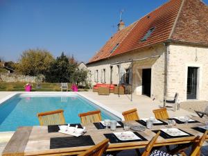 a table and chairs next to a swimming pool at L'Amalgam' in Ainay-le-Vieil