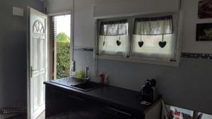 een keuken met een aanrecht en twee ramen met harten erop bij La Bikok in Billy