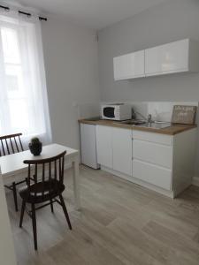 kuchnia z białymi szafkami, stołem i zlewem w obiekcie L'Eau Reine w mieście Saumur