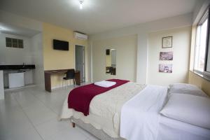 a bedroom with a large white bed and a desk at Hotel Silveira in Bambuí
