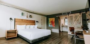 a bedroom with a large white bed and a desk at SCP Colorado Springs Hotel in Colorado Springs