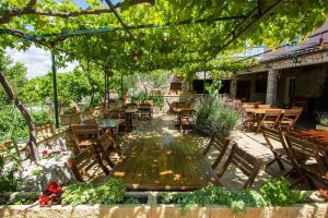 an outdoor patio with tables and chairs and trees at Apartments and Rooms Skalinada in Murter