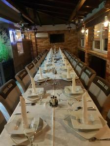 a long table with chairs and plates and wine glasses at Barna Bár Motel&Apartman in Tetélen