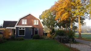 a house with a grass yard in front of it at Gastenverblijf Tjoene in Diepenveen