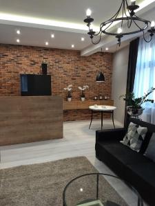 a living room with a black couch and a tv at Apartament Kamea Wieliczka Centrum in Wieliczka