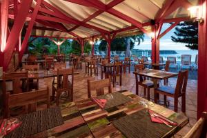 een restaurant met houten tafels en stoelen en de oceaan bij Le Rayon Vert in Deshaies