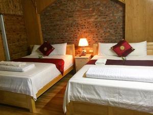 two beds in a room with a brick wall at Tam Coc Green Fields Homestay in Ninh Binh