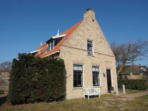 a brick house with a white bench in front of it at De Vergulde Kikker in Baaiduinen