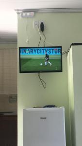 a flat screen tv on a wall above a refrigerator at Chalés AABB Valença RJ in Valença