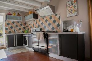 una cucina con elettrodomestici in acciaio inossidabile e armadietti neri di Les Ruchers d'Emile a Landécourt
