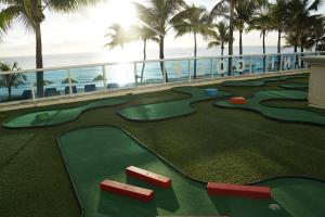 a golf course at a resort with palm trees and the ocean at Ocean Sky Hotel & Resort in Fort Lauderdale