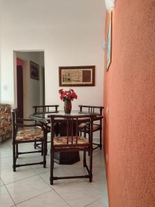 ein Tisch und Stühle mit einer Blumenvase drauf in der Unterkunft Ap. Completo Enseada in Guarujá