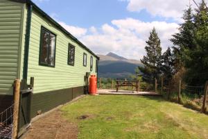 una casa verde con un patio junto a una valla en Glen View, en Taynuilt