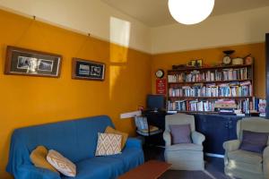 a living room with a blue couch and two chairs at Chester St Backpackers in Christchurch