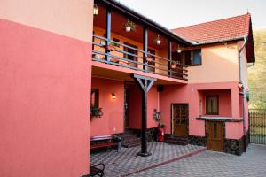 a house with pink and orange walls and a balcony at Pensiunea Darian & David in Orlat