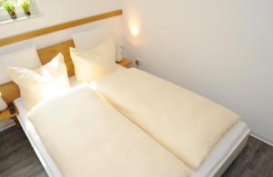 ノルダーナイにあるApartment mit Balkonのベッド(白いシーツ、枕付)